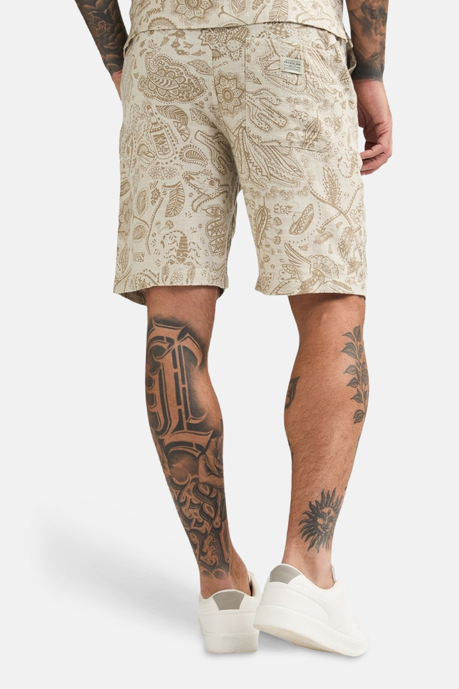 Short beige de Petrol Industries® avec un motif et des tatouages visibles sur les jambes.