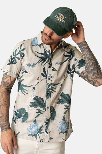 Multikleurig overhemd met korte mouwen van Petrol Industries, met een botanische print en gedragen met een groene pet.
