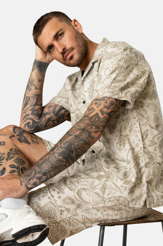 Chemise écru à manches courtes de Petrol Industries®, avec un motif paisley et des tatouages détaillés.