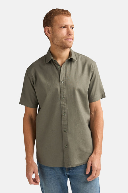 Chemise verte à manches courtes de Petrol Industries®, vue de dos, avec un pantalon en jean et des plis.