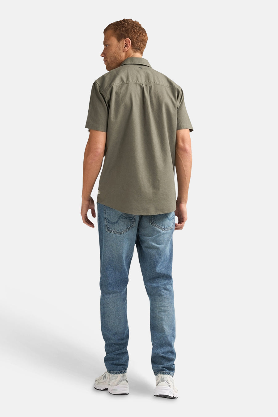 Groen overhemd met korte mouwen van Petrol Industries, gezien van achteren, gedragen met blauwe jeans en witte sneakers.
