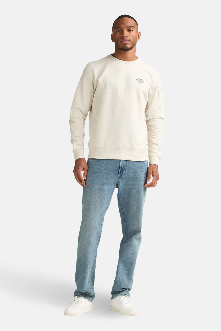Gilet écru avec col rond de Petrol Industries, avec des manches longues et des jeans bleu clair et des baskets blanches.
