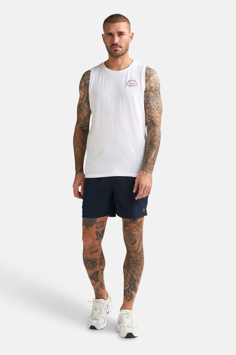 Short de bain bleu de Petrol Industries avec des tatouages sur les jambes et des baskets blanches.