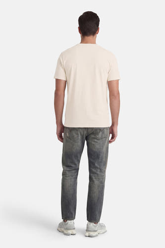 T-shirt écru à manches courtes de Petrol Industries, vu de dos, avec un jean et des baskets blanches.
