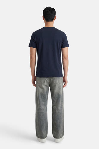 T-shirt bleu à manches courtes de Petrol Industries, vu de dos, avec un jean gris et des chaussures blanches.