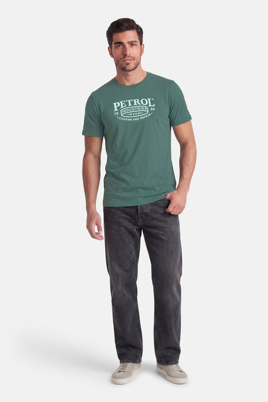 Groen T-shirt met korte mouwen van Petrol Industries, gedragen met donkere spijkerbroek en grijze schoenen.