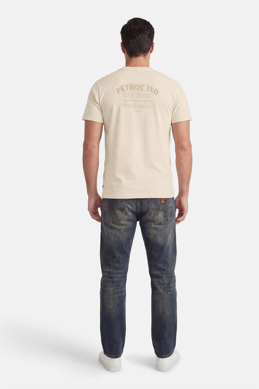 T-shirt écru à manches courtes de Petrol Industries, avec imprimé texte au dos, porté avec un jean et des baskets blanches.