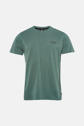 T-shirt vert à manches courtes de Petrol Industries, avec texte imprimé au dos, combiné avec un jean bleu et des chaussures blanches.