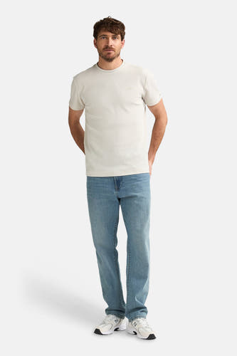 T-shirt écru à manches courtes de Petrol Industries, avec jean et baskets blanches.