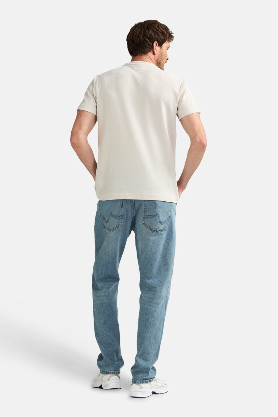 Ecru T-shirt met korte mouwen van Petrol Industries, achterkant, gecombineerd met blauwe jeans en witte sneakers.
