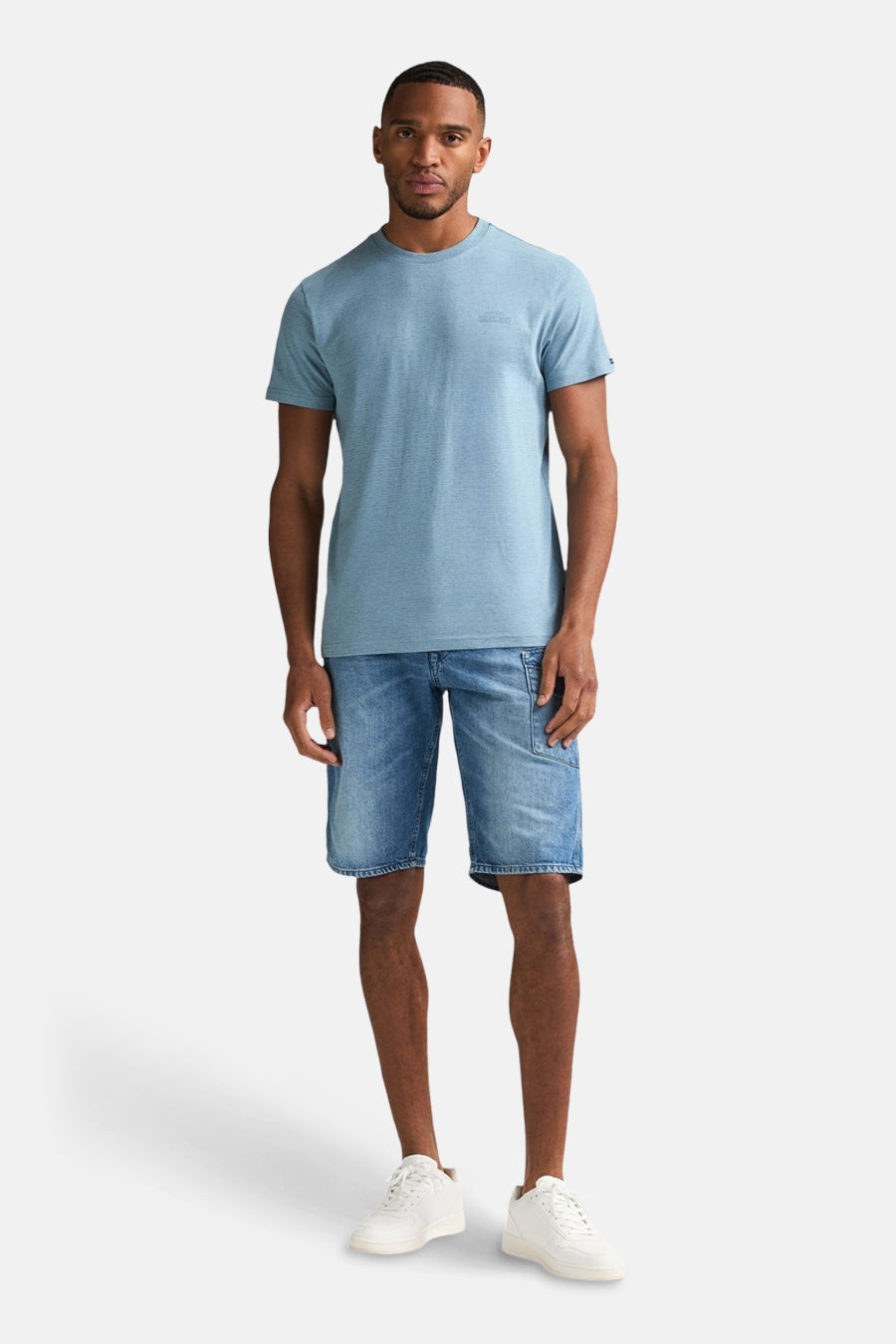 T-shirt bleu à manches courtes de Petrol Industries, porté avec un short en jean et des baskets blanches.