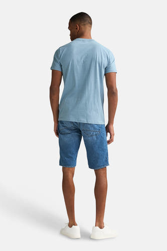 Blauw T-shirt met korte mouwen van Petrol Industries, gezien van achteren, gedragen met denim shorts en witte sneakers.