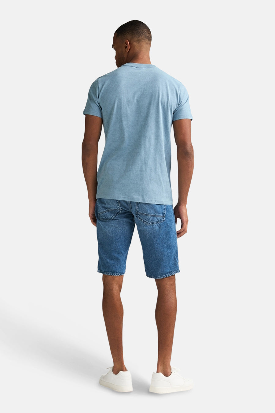 Blauw T-shirt met korte mouwen van Petrol Industries, gezien van achteren, gedragen met denim shorts en witte sneakers.