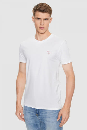 T-shirt blanc à manches courtes de Guess avec un petit logo sur la poitrine, porté avec un pantalon de cuir.