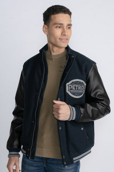 Veste courte bleue de Petrol Industries avec des manches noires et un logo brodé.