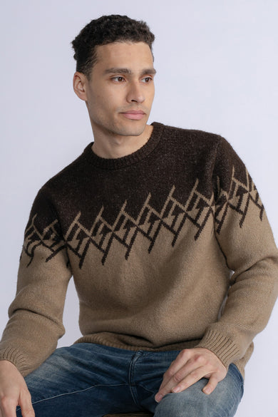 Pull marron avec col rond de Petrol Industries®, avec un motif géométrique et porté avec un jean bleu.
