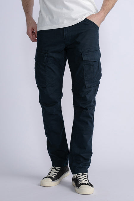 Jean cargo bleu de Petrol Industries avec des poches sur les côtés et des baskets noires.