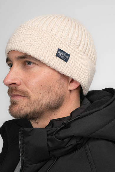 Chapeau beige de Petrol Industries, avec une texture à larges rayures et un étiquette marque bleu foncé.