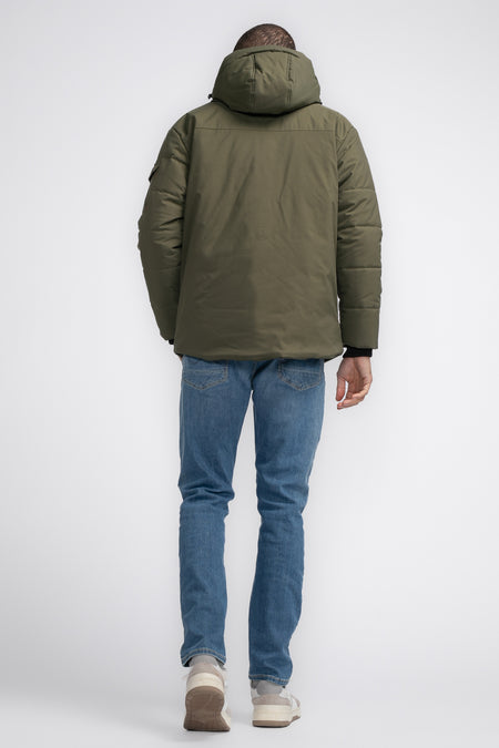 Veste de pluie khaki de Petrol Industries, vue arrière avec capuchon, associée à un short en jean et des baskets.