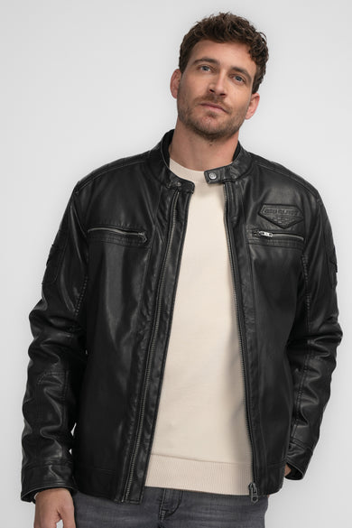 Manteau court noir de Petrol Industries, avec des poches à glissière et un pull clair en dessous.