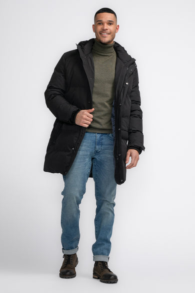 Manteau noir long de Petrol Industries, avec un colbert et des jeans bleu clair et des chaussures brunes.