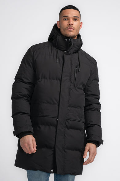 Veste longue noire de Petrol Industries®, avec capuche et poches, portée sur un jean.
