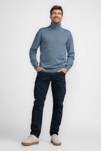 Blauwe coltrui van Petrol Industries, met lange mouwen en gedragen met een donkere broek en sneakers.