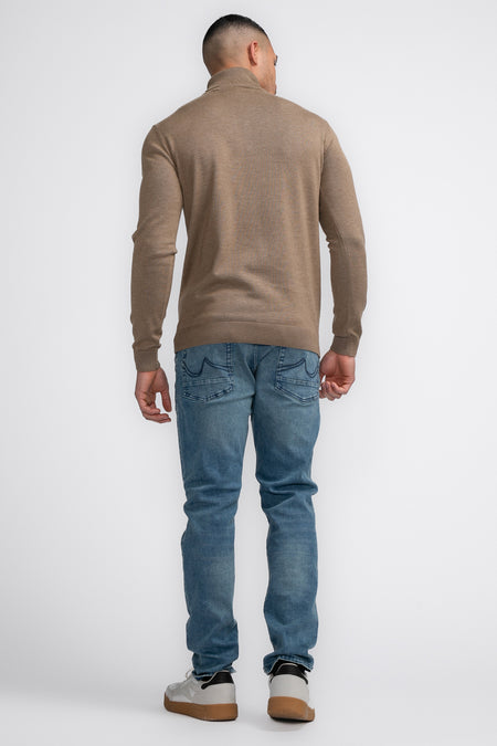 Pull beige à col montant de Petrol Industries, avec des manches longues et associé à des jeans et des baskets.