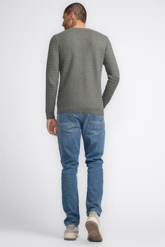 Groene trui met ronde hals van Petrol Industries, met een geweven textuur, gecombineerd met blauwe jeans en sneakers.
