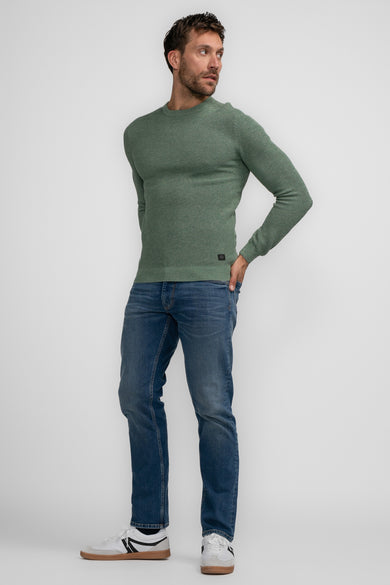 Pull vert à col rond de Petrol Industries, à manches longues et porté avec un jean et des baskets.