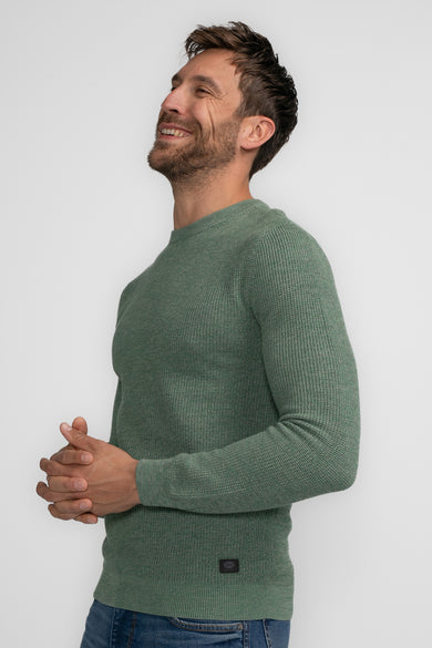 Pull vert avec col rond de Petrol Industries®, en structure gaufrée et porté avec un jean.