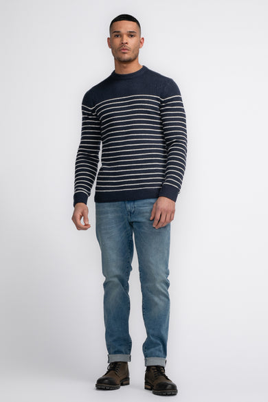 T-shirt bleu avec col rond de Petrol Industries®, à rayures horizontales blanches, associé à des jeans et des bottes.