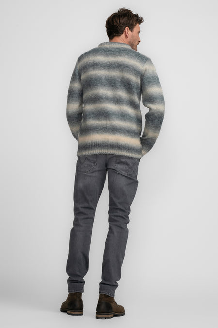 T-shirt rond col bleu de Petrol Industries, avec des rayures horizontales et des jeans gris et des bottes brunes.