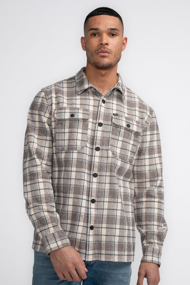 Chemise brune à longues manches de Petrol Industries, avec des accents bleus, vue de derrière et portée avec un jean.