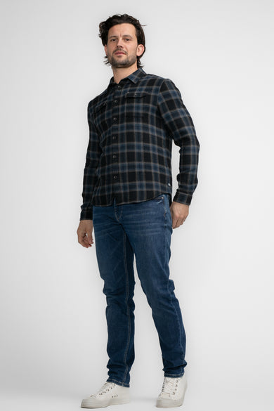 Chemise noire à manches longues de Petrol Industries, avec un motif rayé, associée à des jeans et des baskets blanches.
