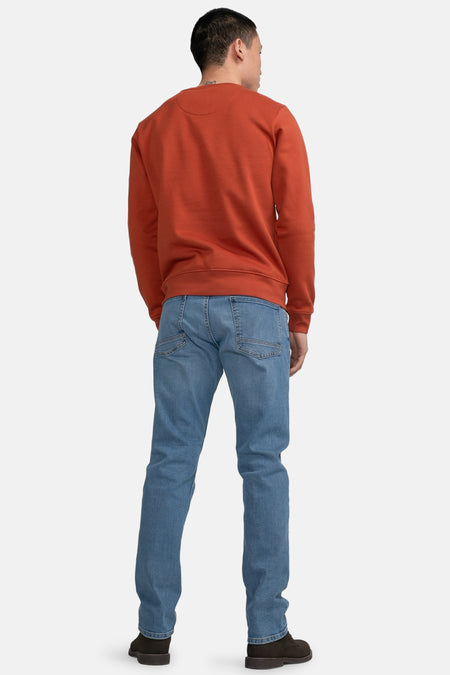 Pull-over rouge de Petrol Industries, avec des manches longues, porté avec des jeans bleus et des chaussures sombres, vue arrière.