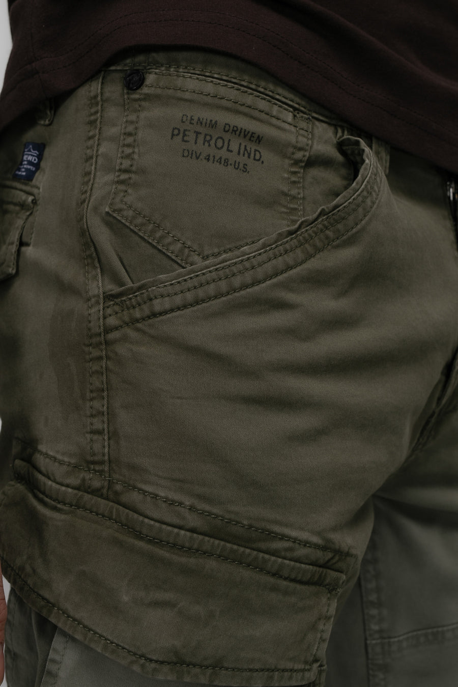 Pantalon de travail vert de Petrol Industries avec des poches et un vêtement marron au-dessus du pantalon.