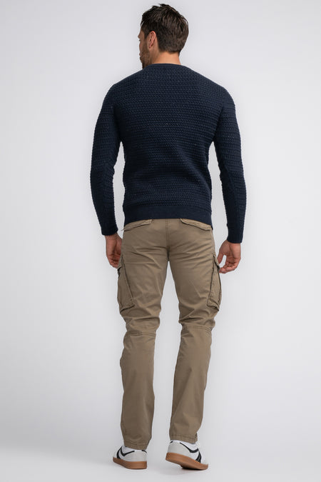 Pantalon cargo Bruine de Petrol Industries®, dos avec grandes poches latérales, porté avec un pull bleu foncé et des baskets blanches.