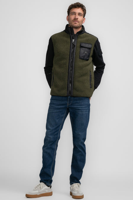 Gilet vert de Petrol Industries Industries avec Industries no noir et et et et et, porté un un-shirt-shirt noir, des jeans et des baskets blanches.