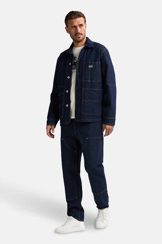Veste en jeans bleu de Petrol Industries® avec fermeture à boutons et poches brodées, portée avec un T-shirt blanc et des jeans foncés.