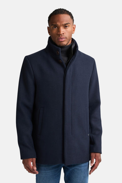 Manteau long bleu de Petrol Industries, avec une capuche et un homme en veste grise et en jeans bleus.