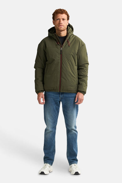 Veste courte verte de Petrol Industries, avec un capuchon, portée avec des jeans et des baskets blanches.