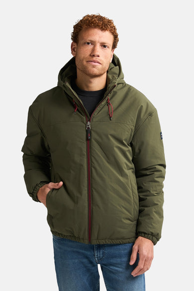 Veste courte verte de Petrol Industries, avec capuche et détails rouges, portée sur une chemise sombre.
