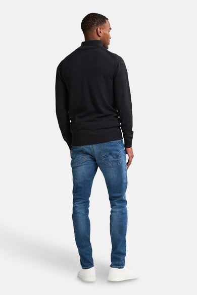 Gilet noir de Petrol Industries, vu de de l'arrière, associé à un jean bleu et des baskets blanches.