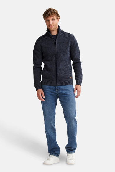 Gilet bleu de Petrol Industries avec fermeture éclair, associé à des jeans et des baskets blanches.