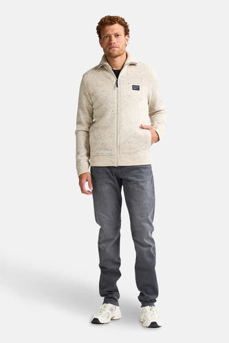 Manteau ecru court de Petrol Industries, avec des manches longues et une fermeture éclair, associé à un jean gris et des baskets.