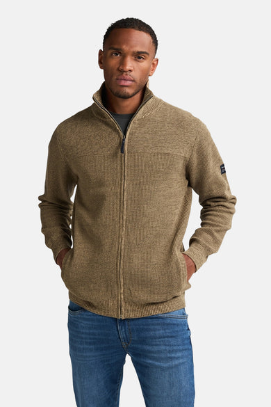 Gilet beige de Petrol Industries avec fermeture à glissière et poches, porté avec un t-shirt foncé et des pantalons en denim.