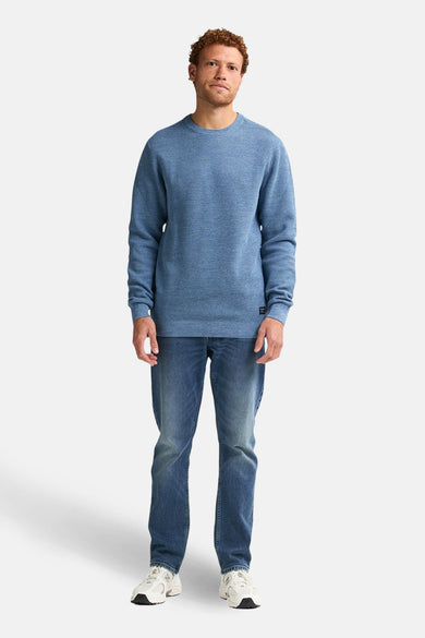 T-shirt bleu avec col rond de Petrol Industries®, à longues manches, porté avec des jeans et des baskets.