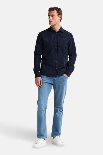 Chemise bleue à manches longues de Petrol Industries®, avec un motif de carreaux subtil, associée à des jeans et des baskets blanches.