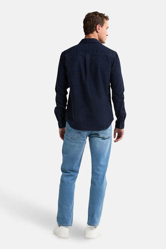 Chemise bleue à manches longues de Petrol Industries, avec un motif à carreaux, associée à des jeans et des baskets blanches.